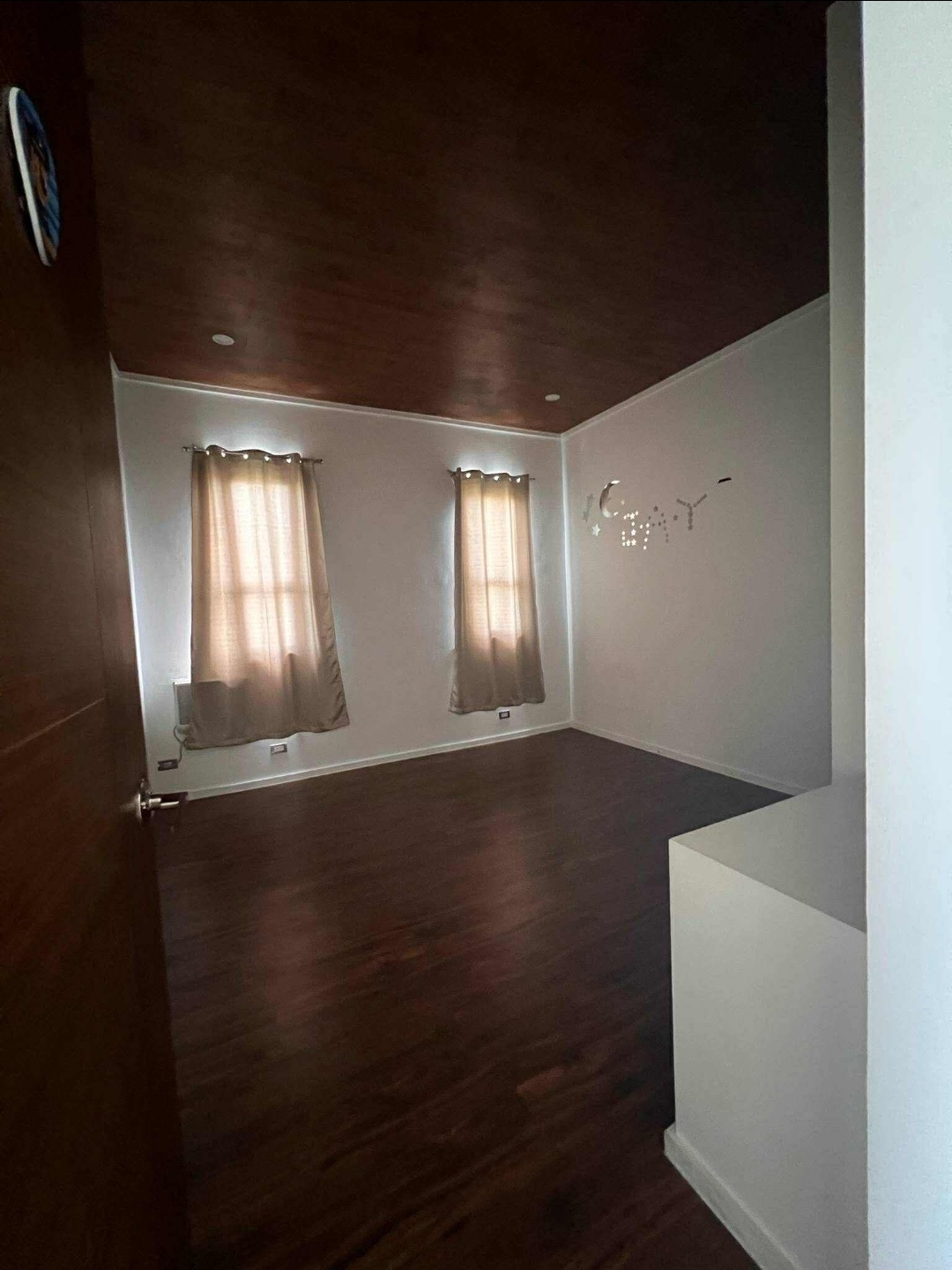 Secondary bedroom with dark wood flooring and twin windows