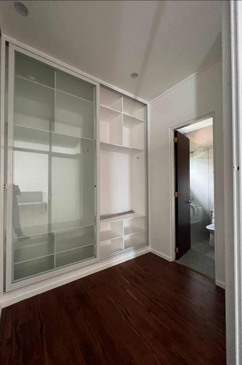 Master walk-in closet with sliding frosted-glass doors leading to the en-suite bath