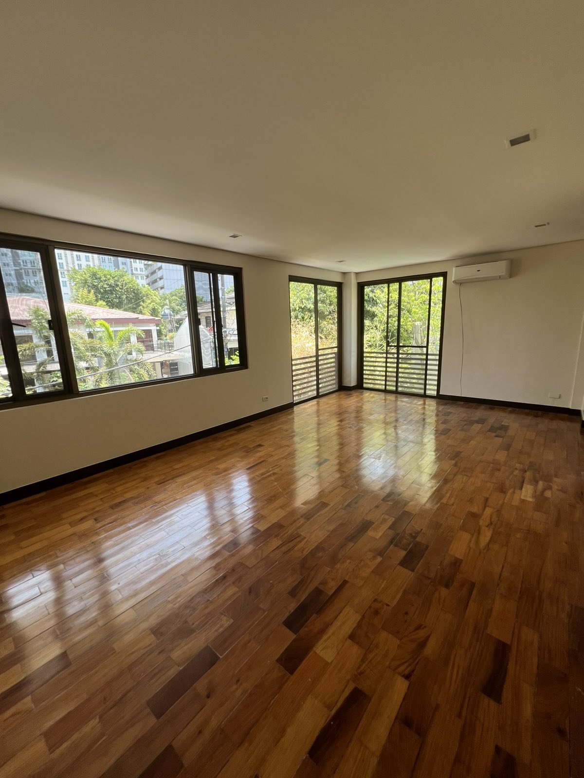 Light-filled living area with warm parquet floors and balcony