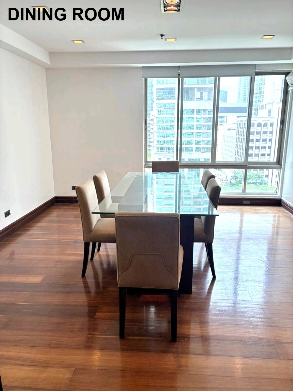Dining area with glass table beside floor-to-ceiling city-view windows