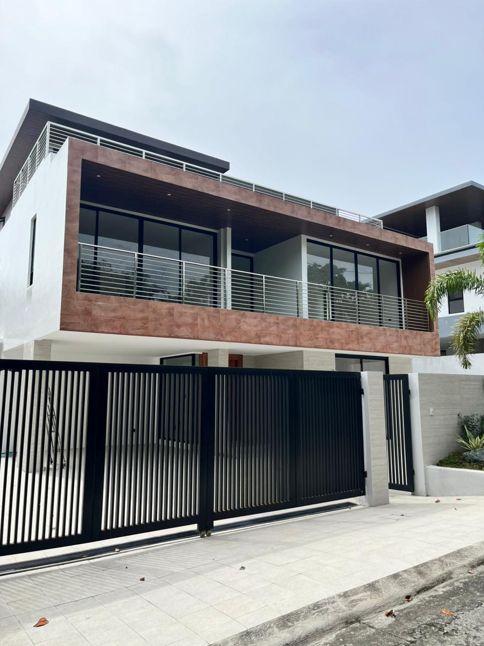 Brand new three-storey modern mansion facade with terracotta accents and automated gate