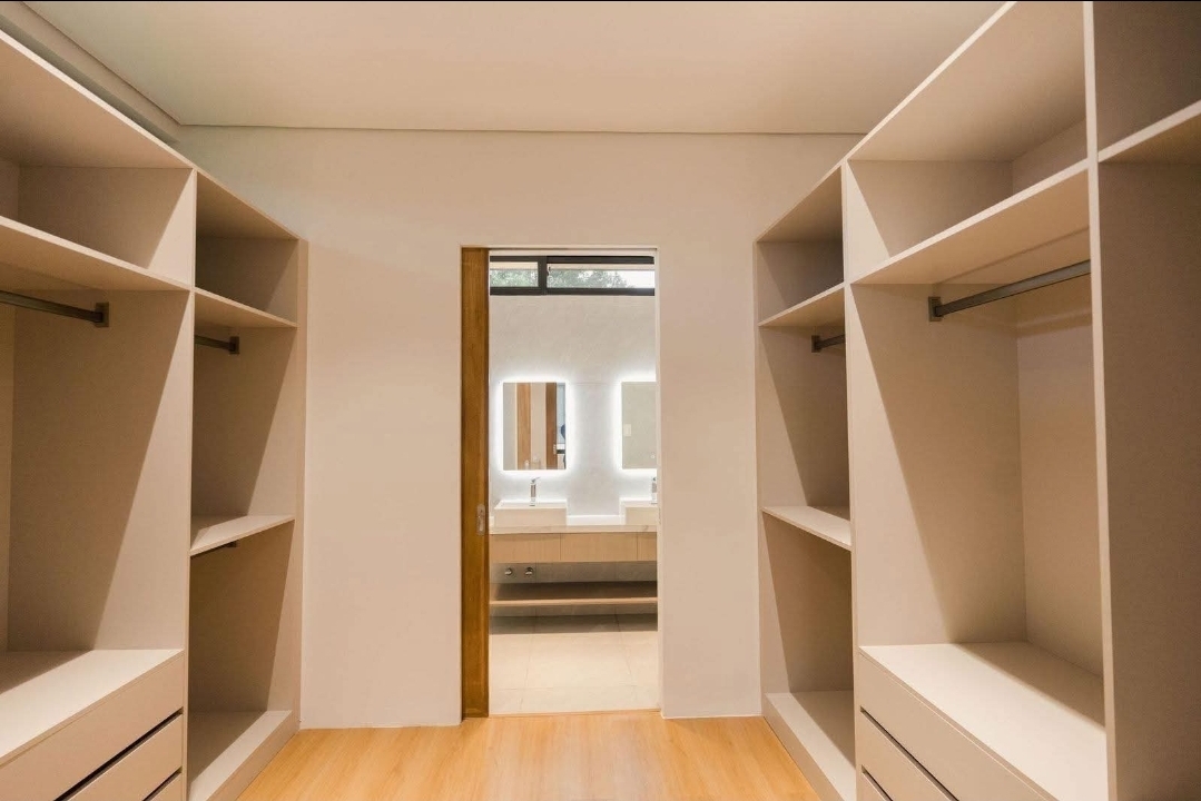 Walk-in closet with open shelving leading to the master bathroom