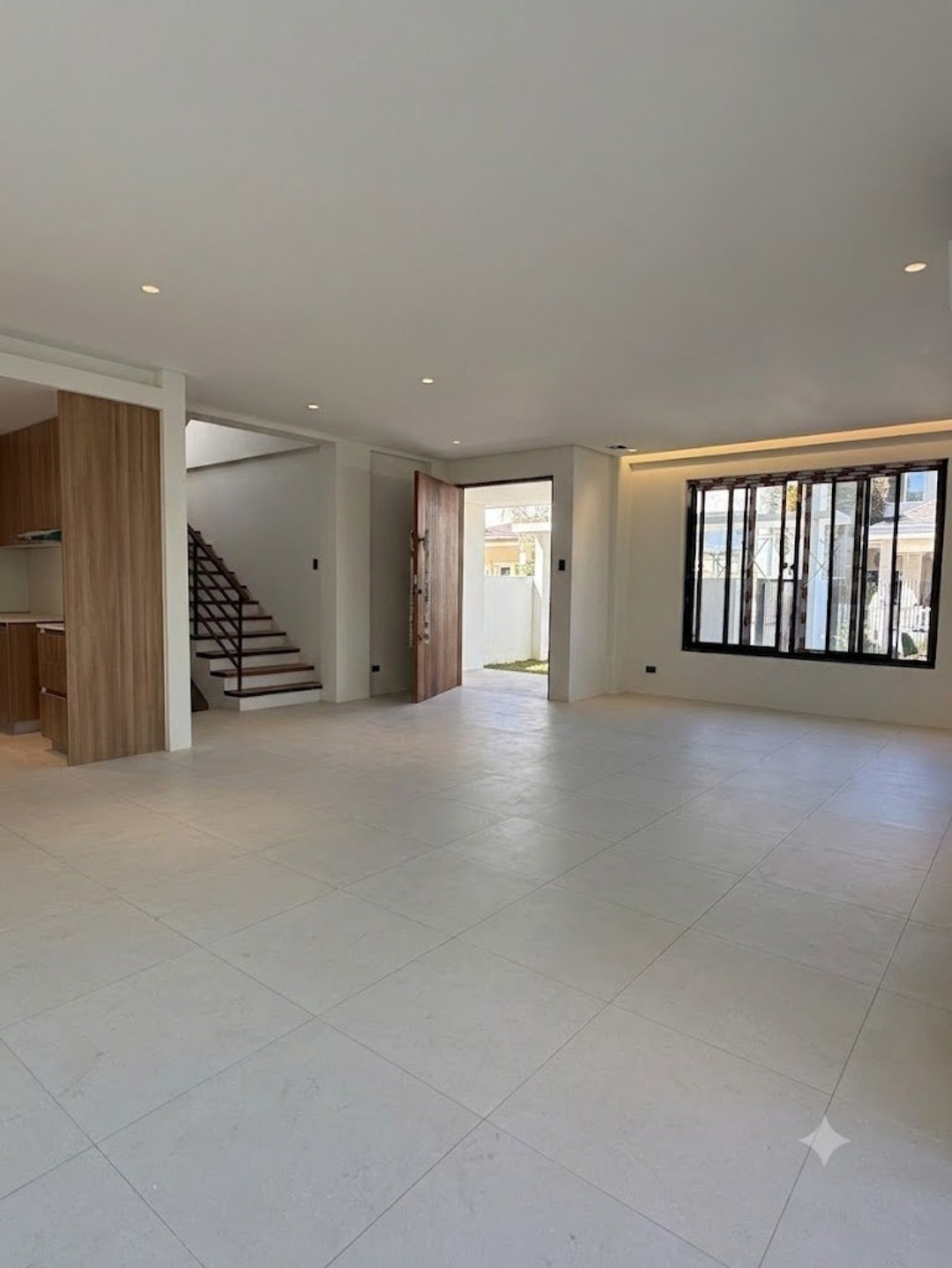 Open living area with staircase, wood cabinetry, and large-format tile flooring