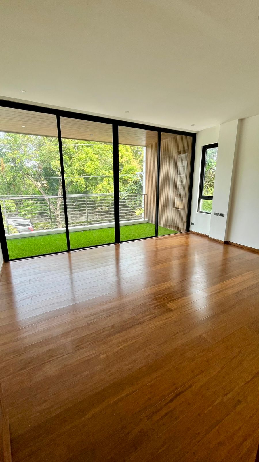 Bedroom with floor-to-ceiling glass, wood-slat accent wall, and private balcony