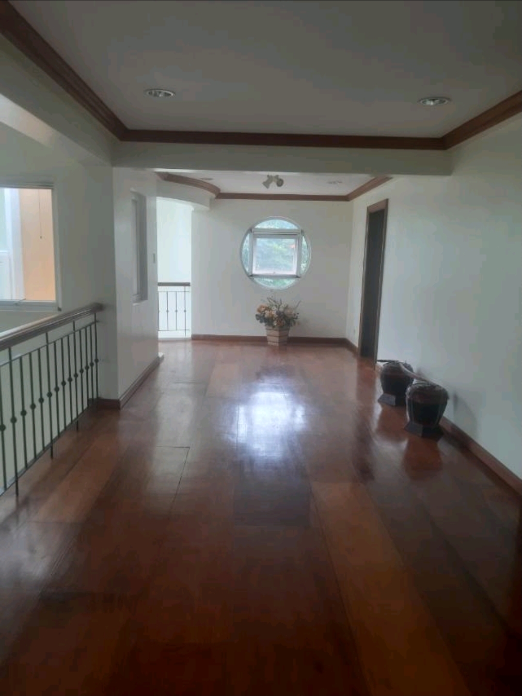 First-floor landing with wide narra plank flooring and wrought-iron railing