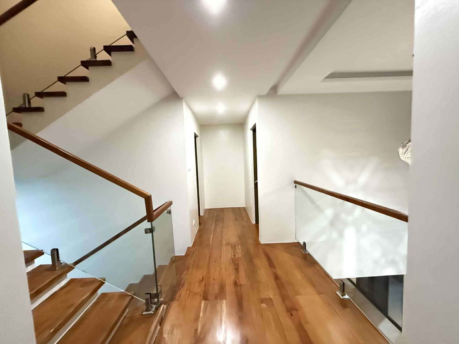 Upper-floor landing and hallway with wood flooring and glass railings