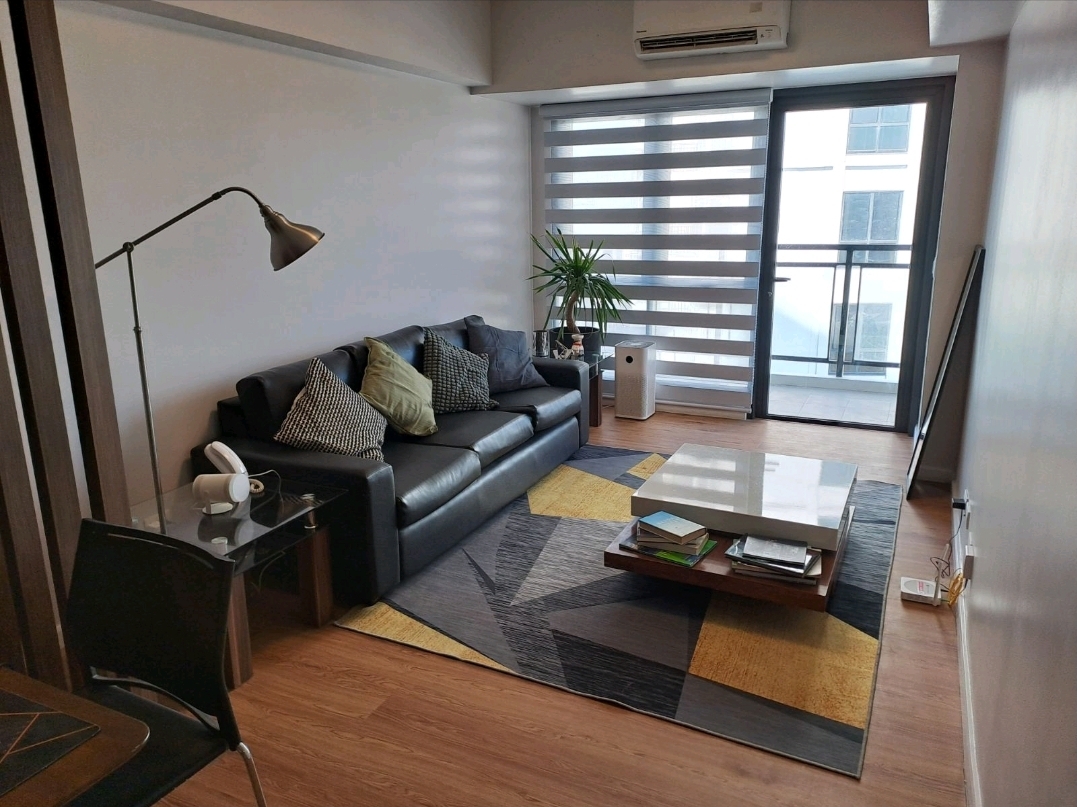 Living area with black leather sofa, geometric rug, and balcony access