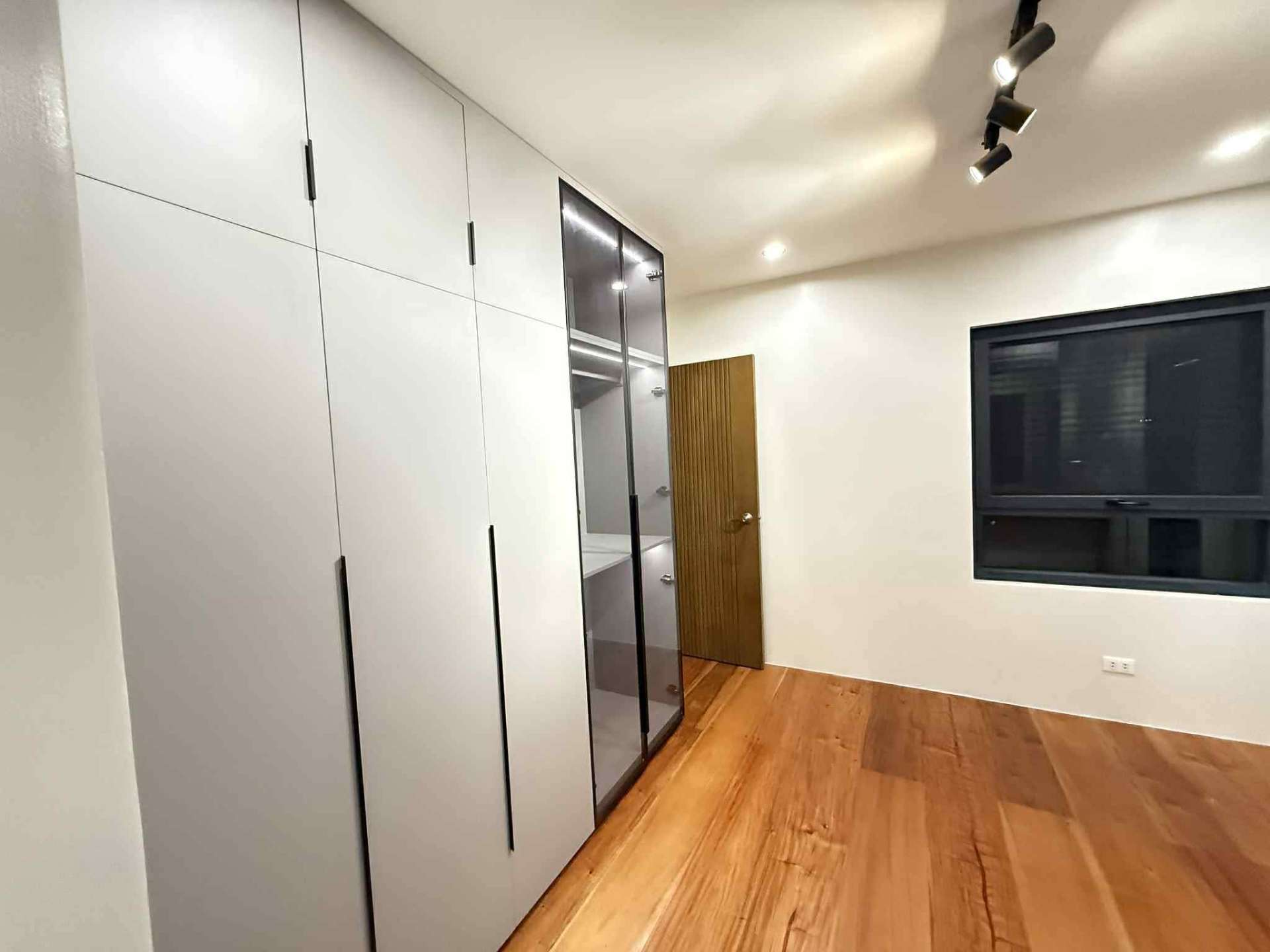 Bedroom with full-height built-in cabinets and solid wood flooring