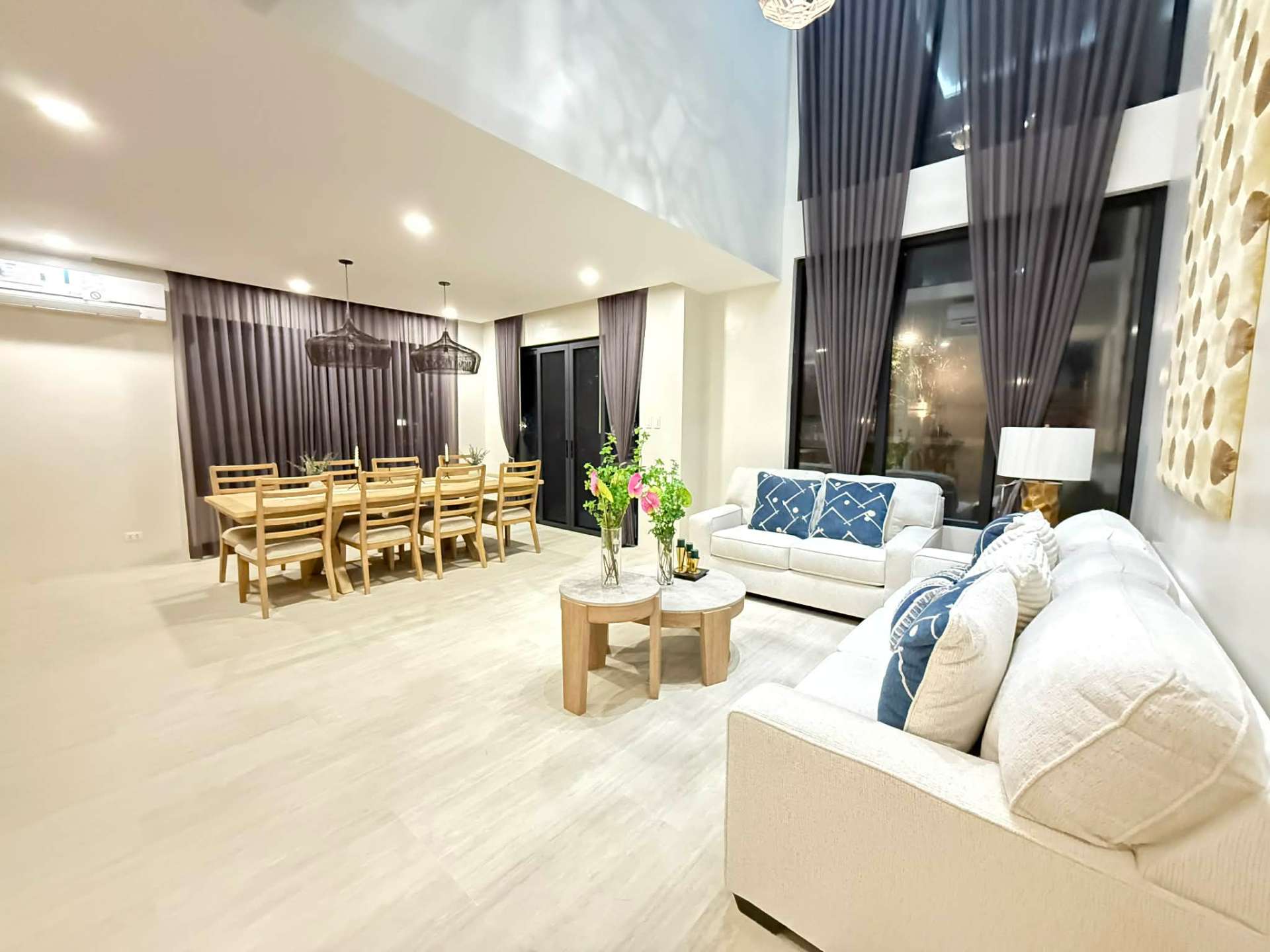 Double-height living and dining area with floor-to-ceiling glass windows
