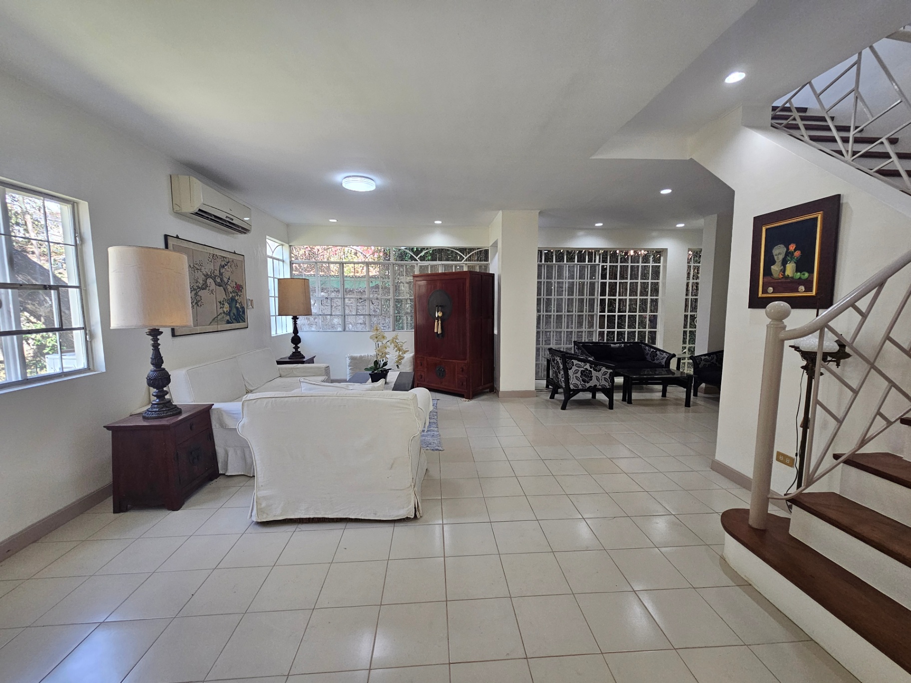 Bright open living area with white tile floors, twin lamps, and large windows
