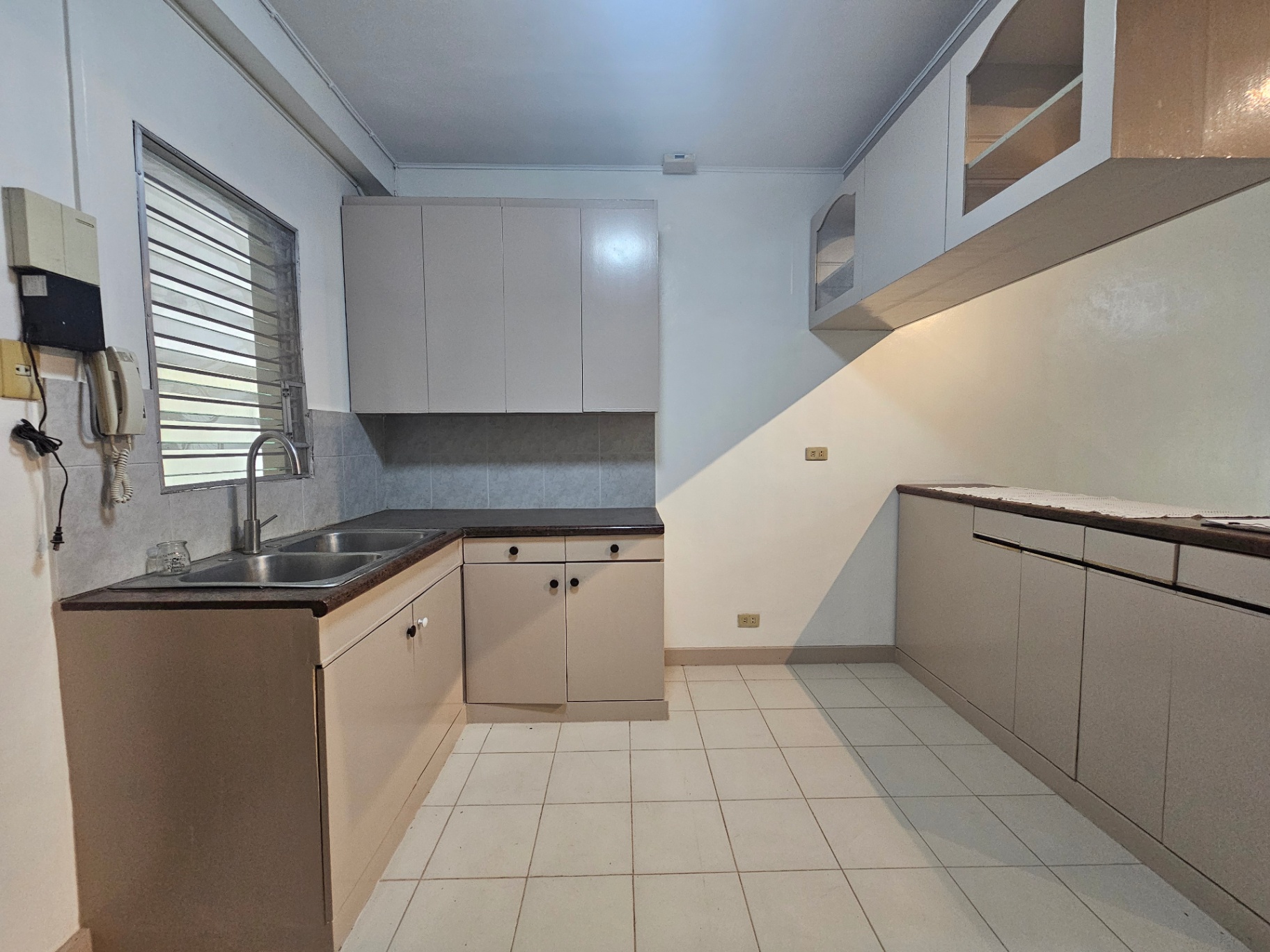 Clean L-shaped kitchen with double sink and ample cabinets