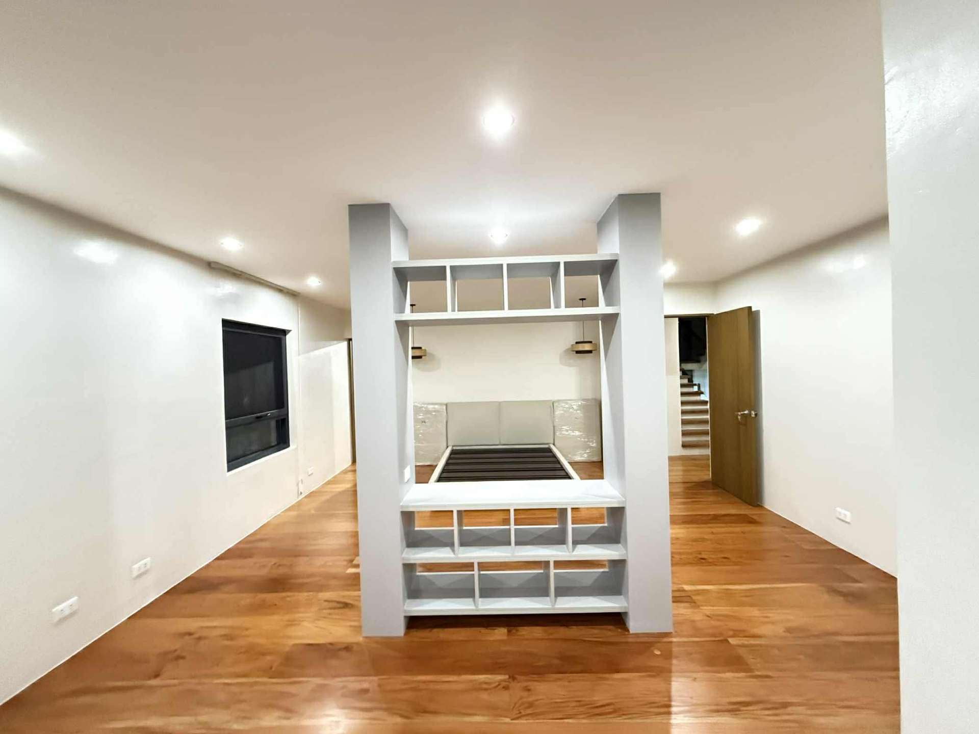 Bedroom with built-in platform bed, shelving, and solid wood flooring