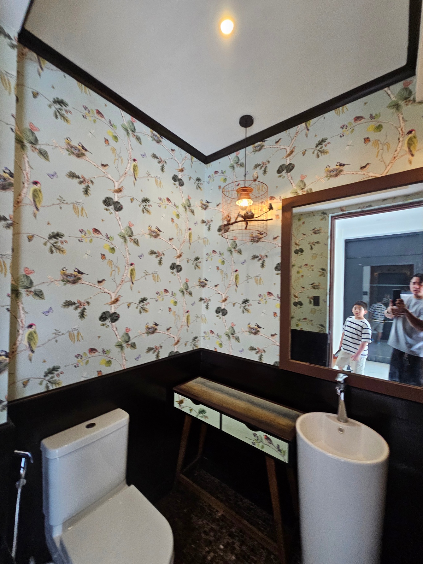 Designer powder room with hand-painted floral wallpaper and birdcage pendant light