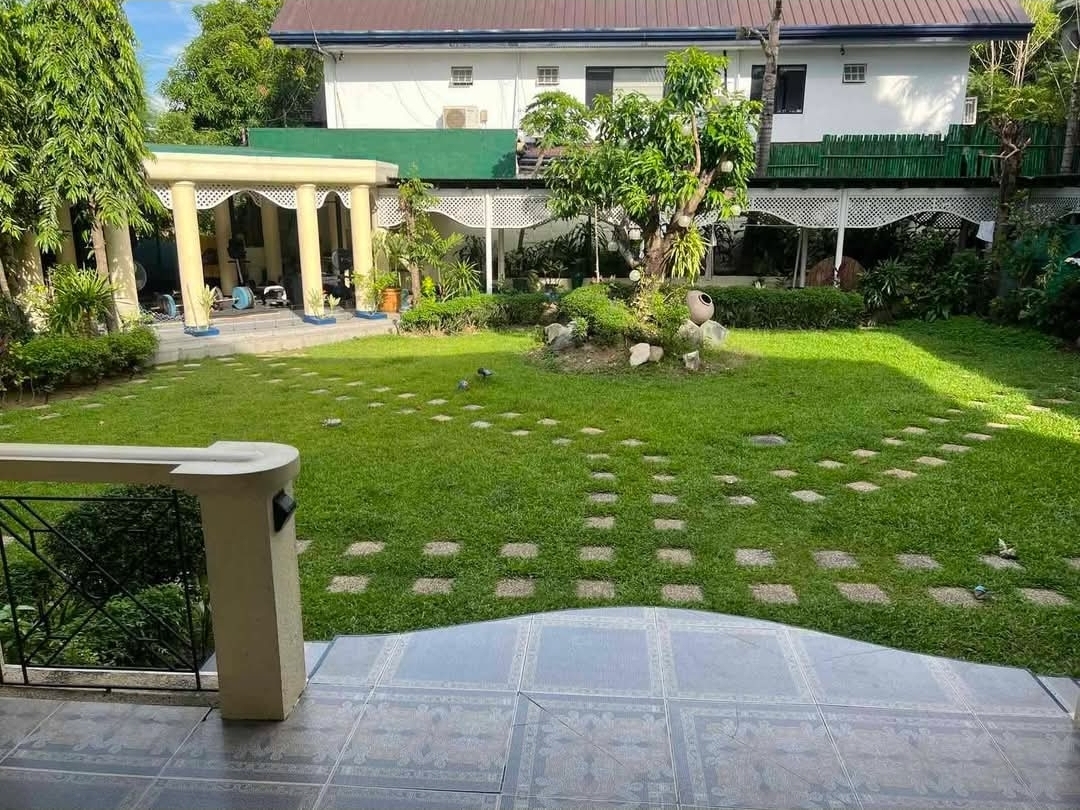 Expansive garden with mature trees and patterned stone paving viewed from the terrace