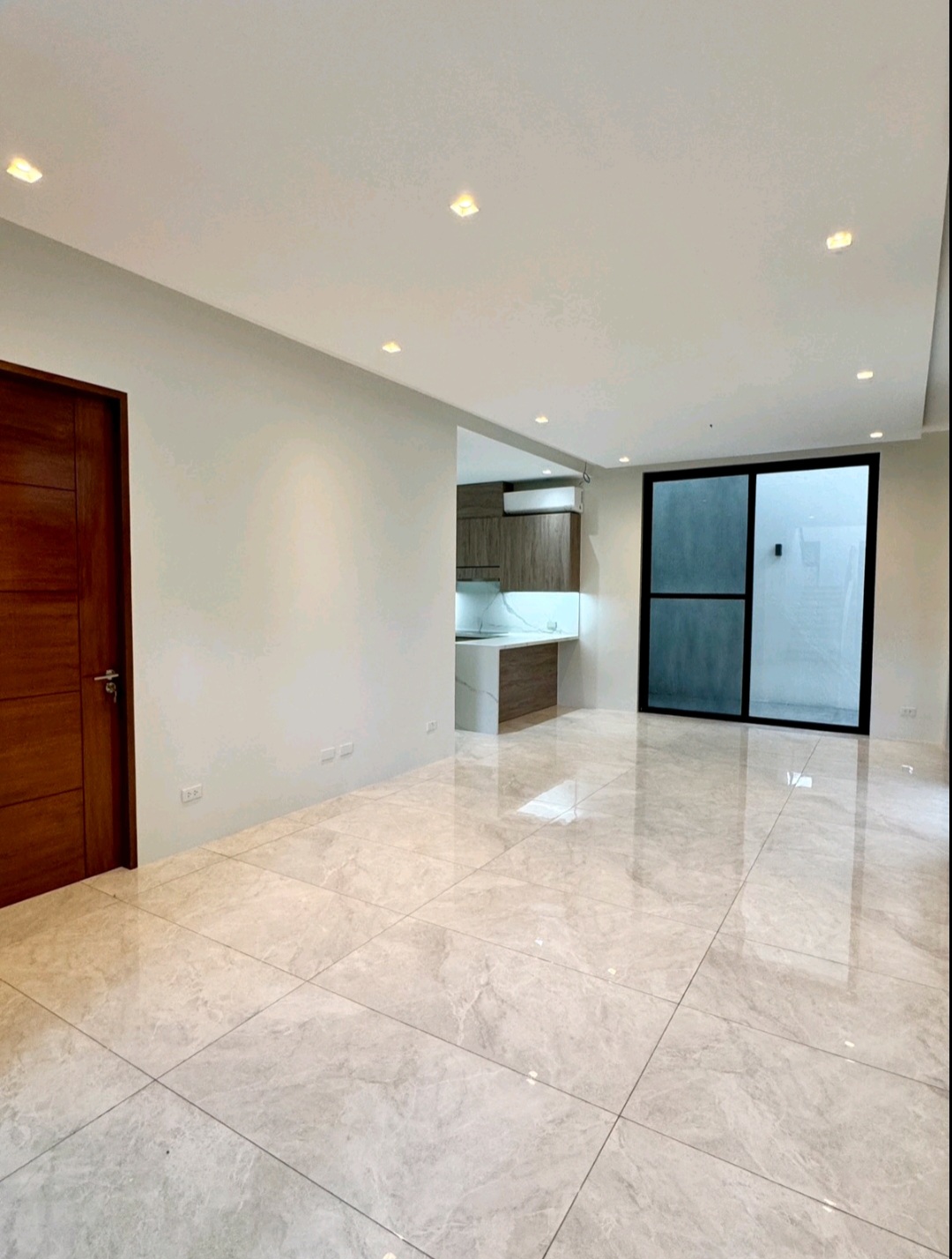 Open living area with polished marble flooring and glass door to the service court