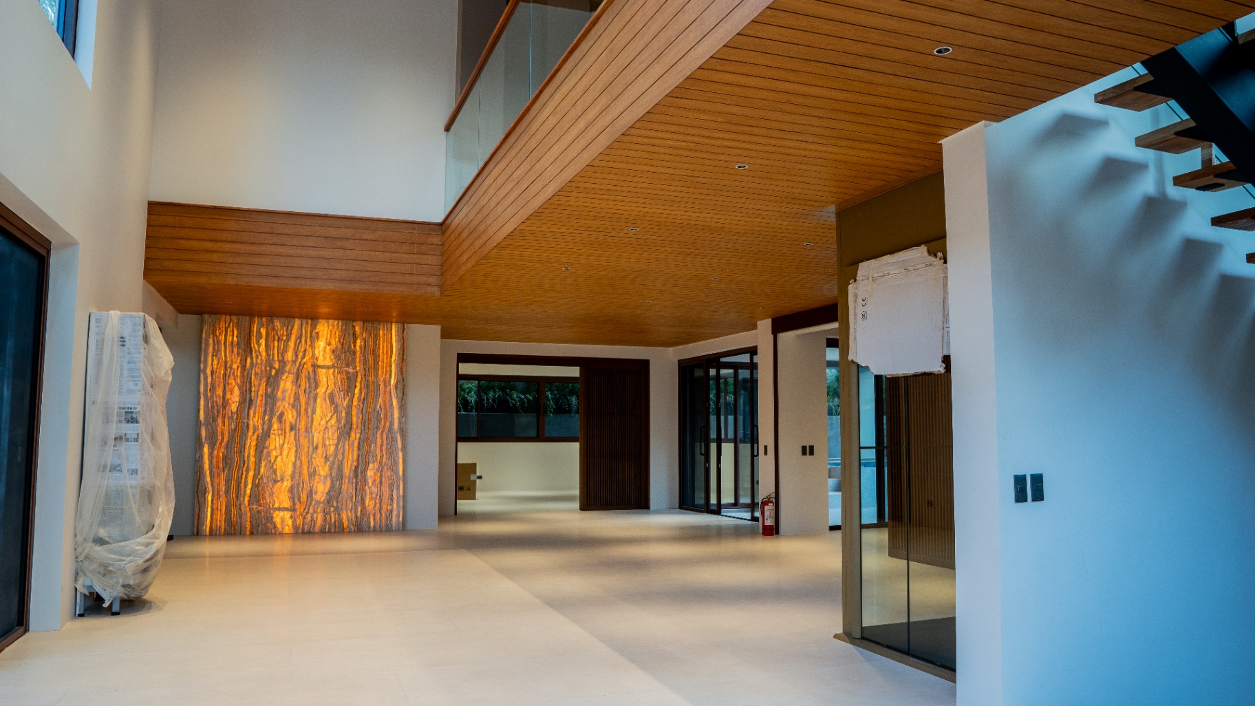 Double-height foyer with backlit travertine onyx accent wall and narra ceiling