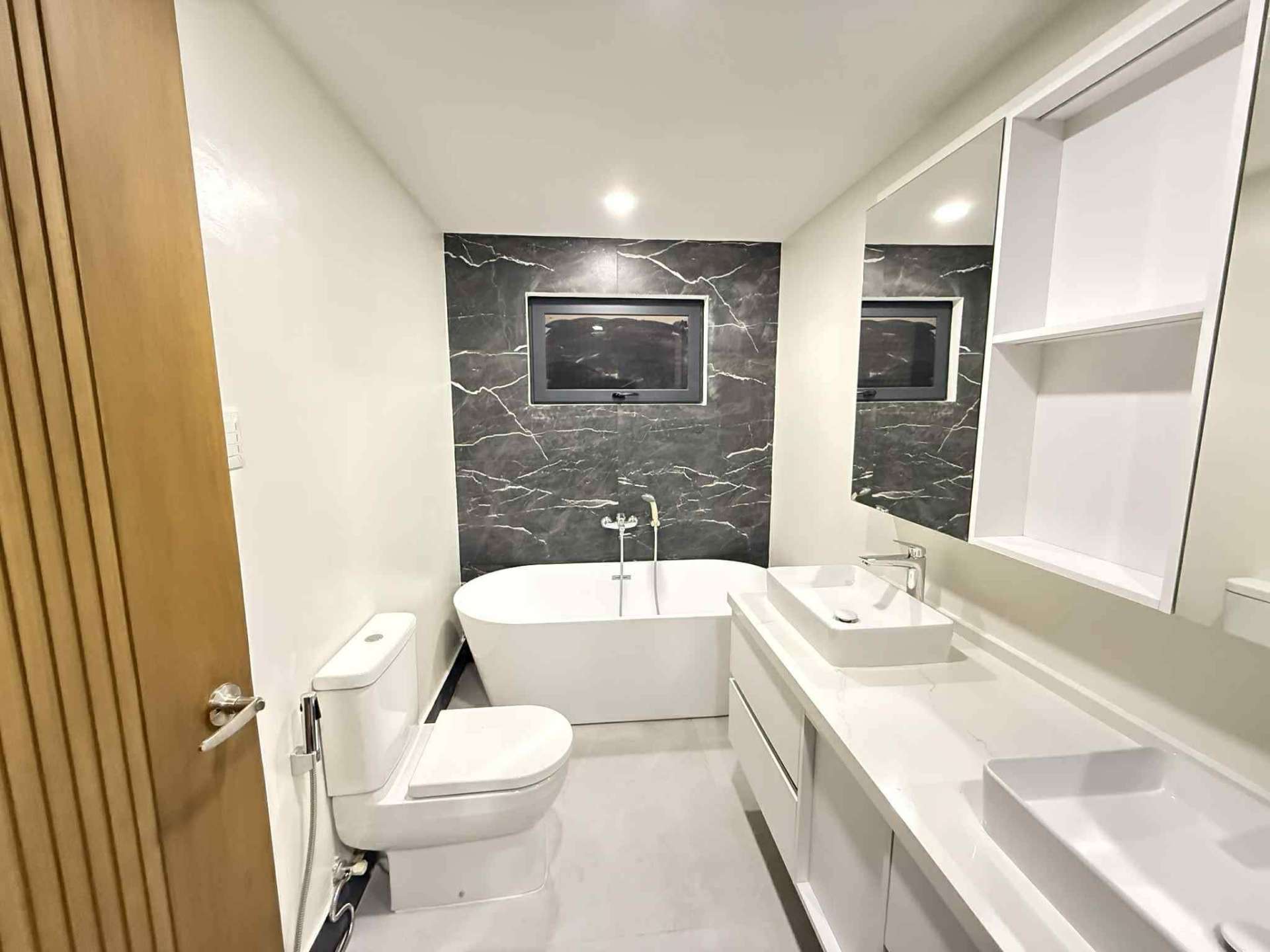 Bathroom with freestanding soaking tub, window, and floating vanity