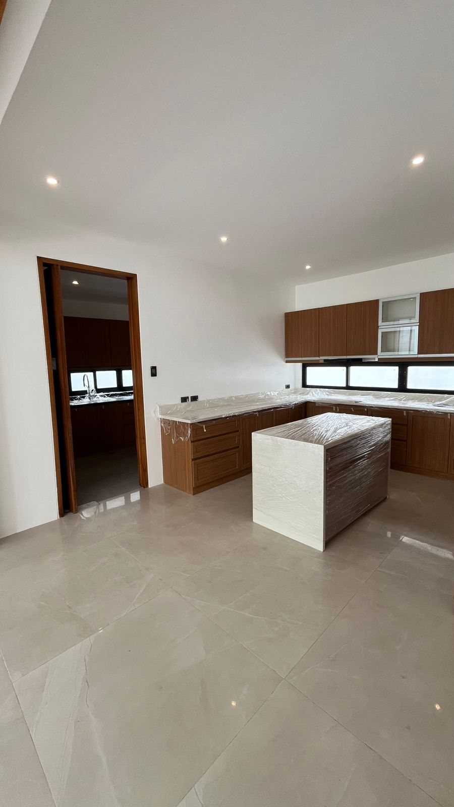 Modern kitchen with solid surface countertops, island, and dedicated service kitchen beyond