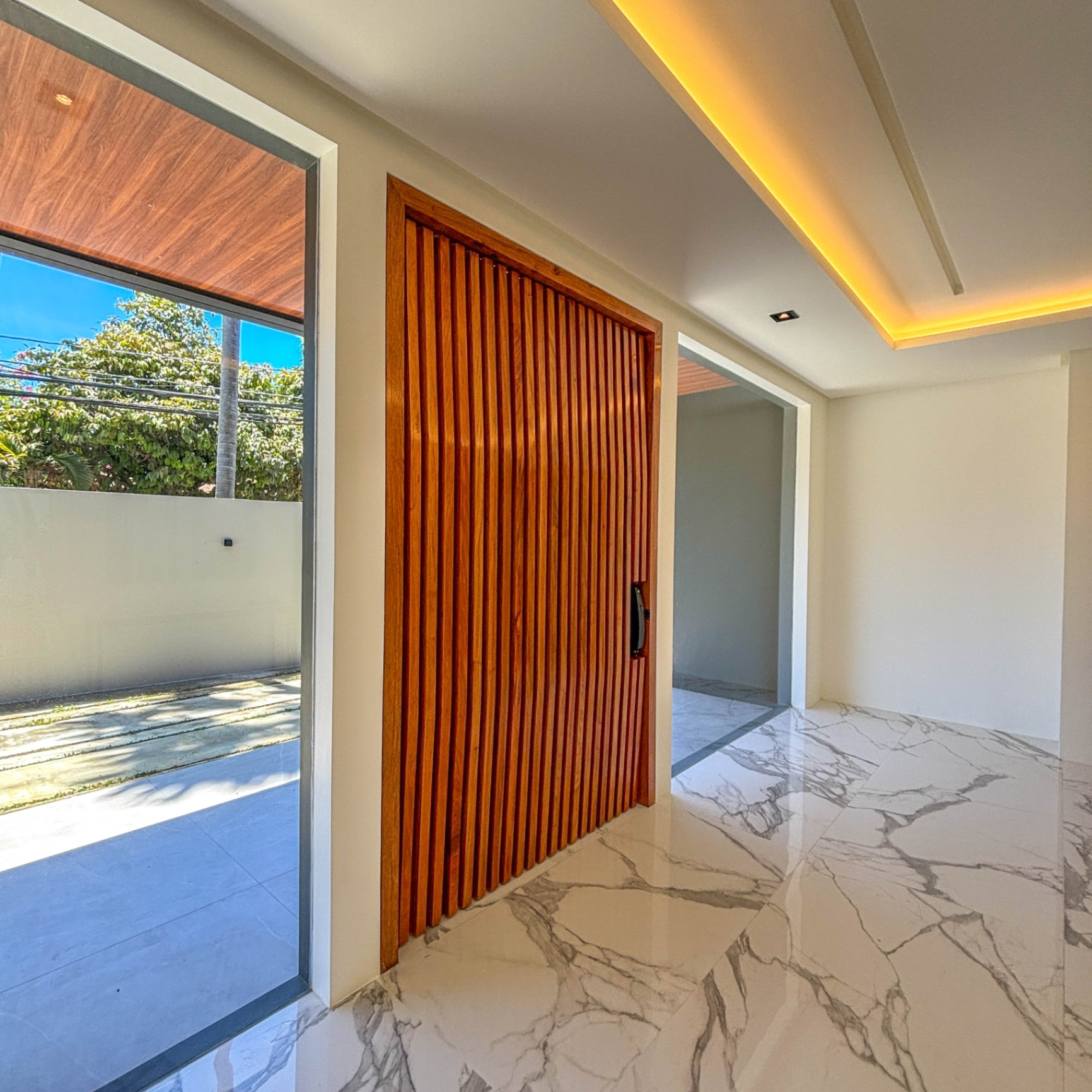 Entry foyer with slatted narra pivot door and marble flooring