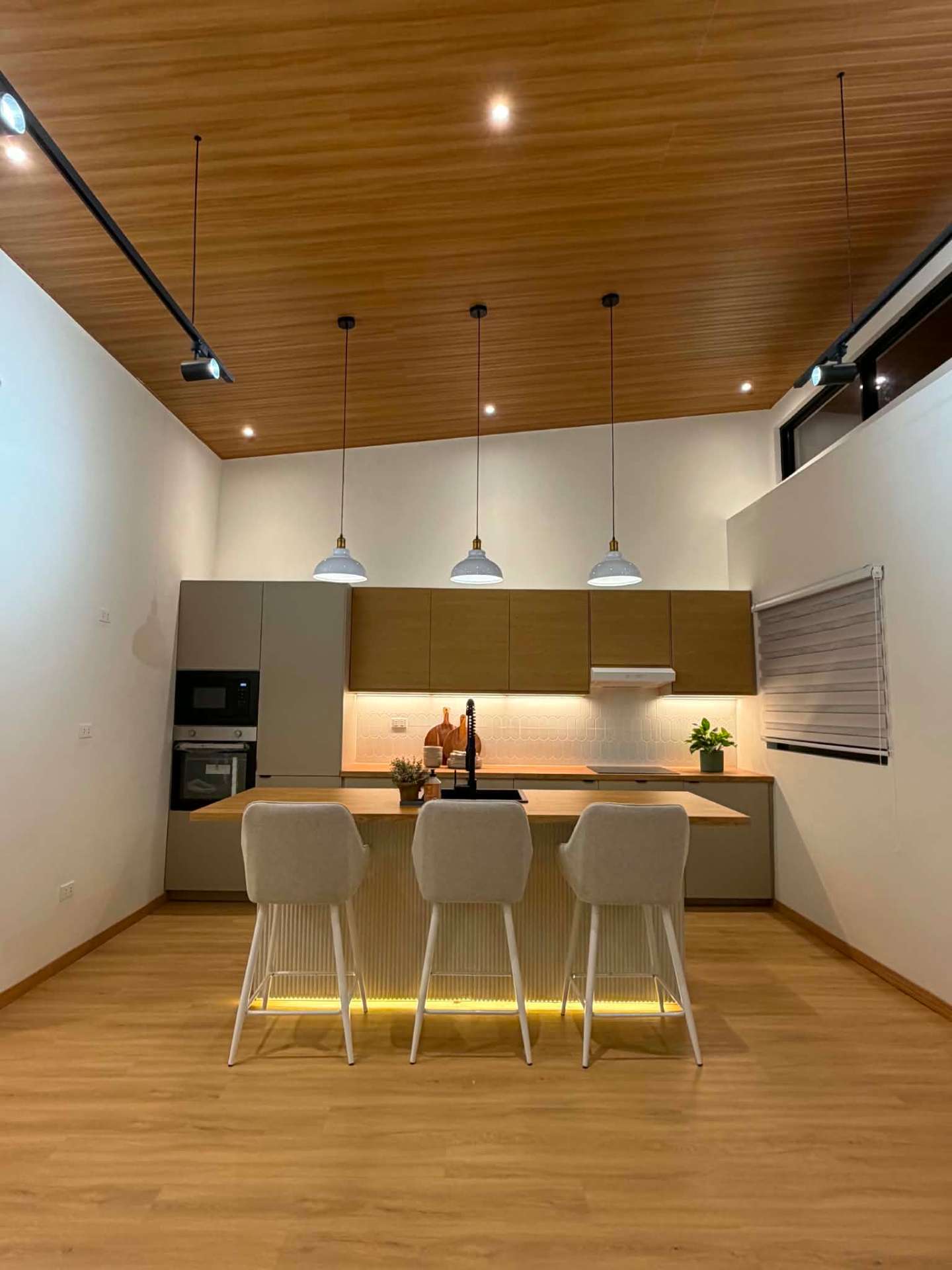 Clean kitchen with island counter, built-in oven and microwave, and pendant lighting