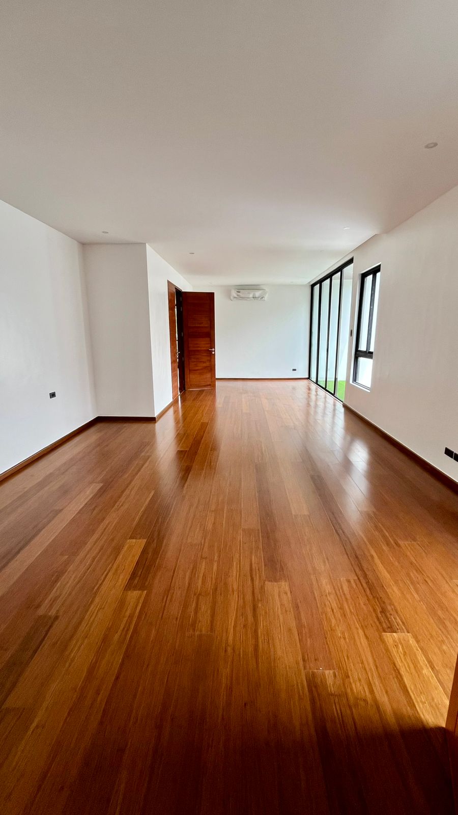 Bright living space with natural oak wood floors, solid wood door, and garden views