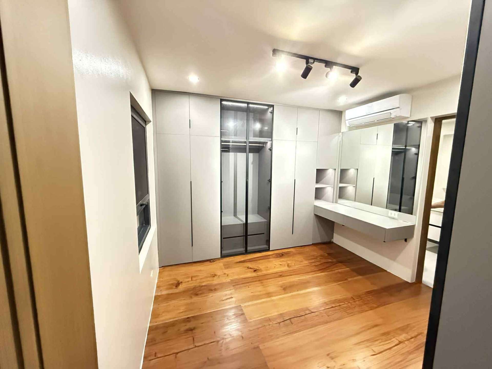 Walk-in closet with built-in cabinets, vanity, and dressing mirror