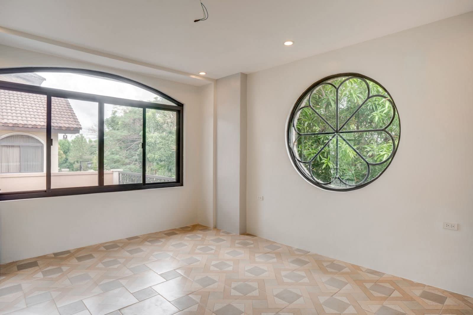 Bright bedroom with arched window and decorative round clover window