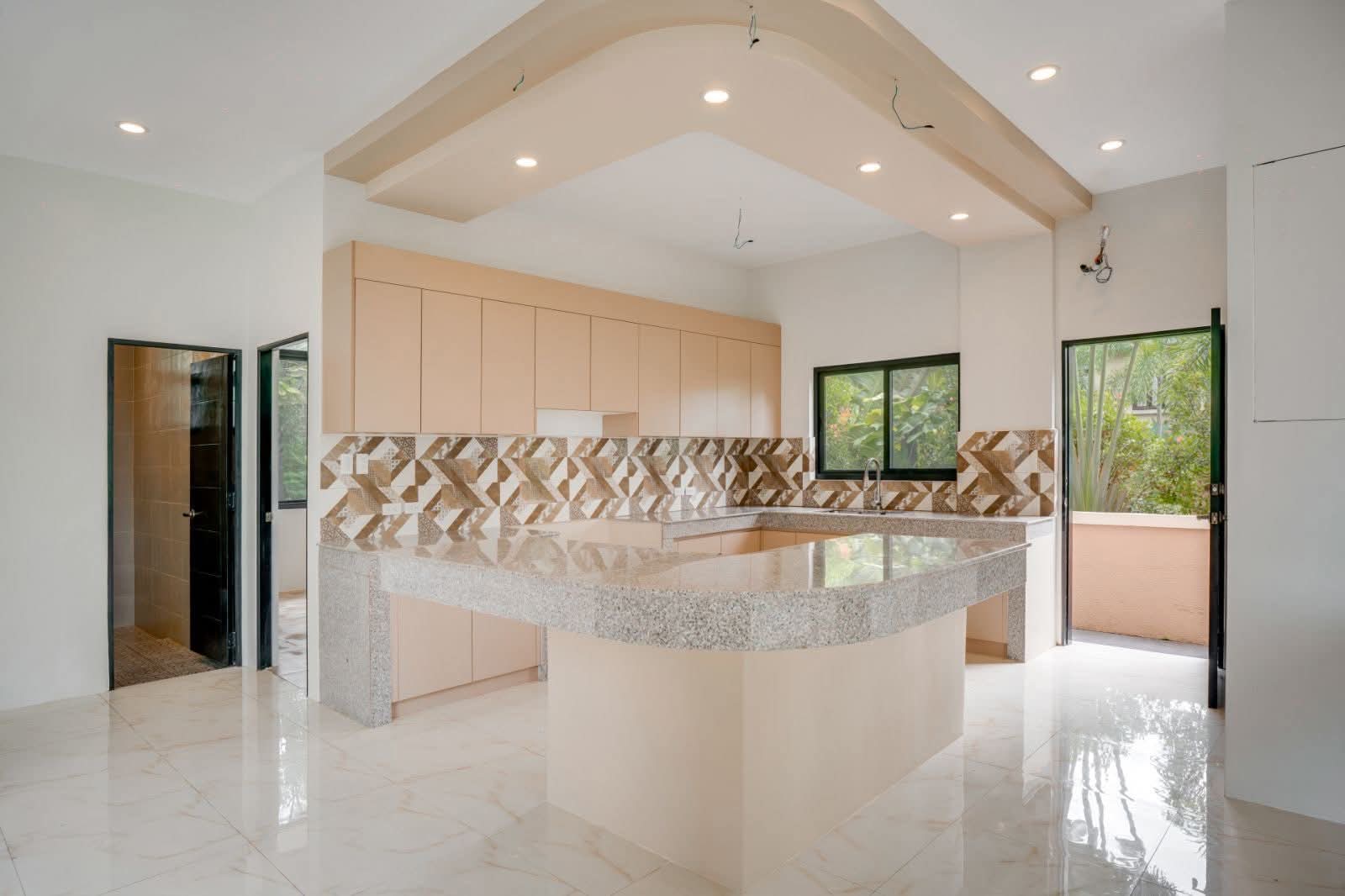 Open kitchen with granite island, cabinetry, and patterned backsplash