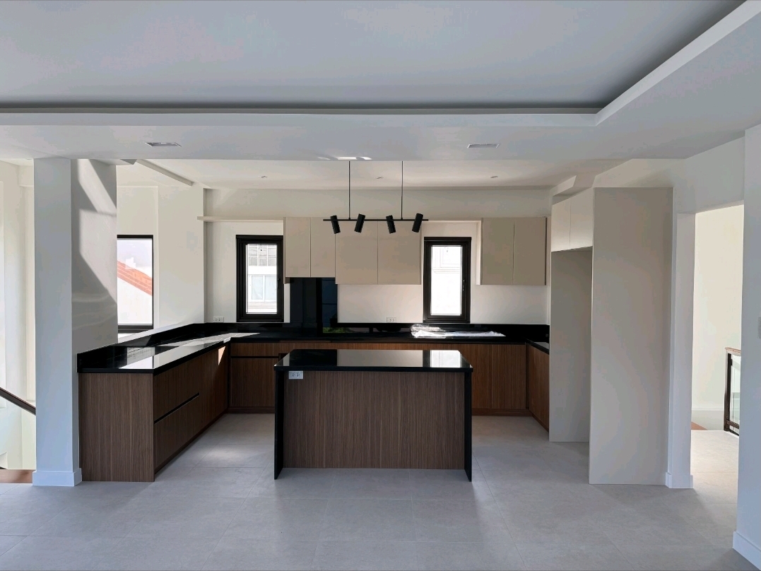 Modern kitchen with island, black granite counters, warm wood cabinetry and hood over