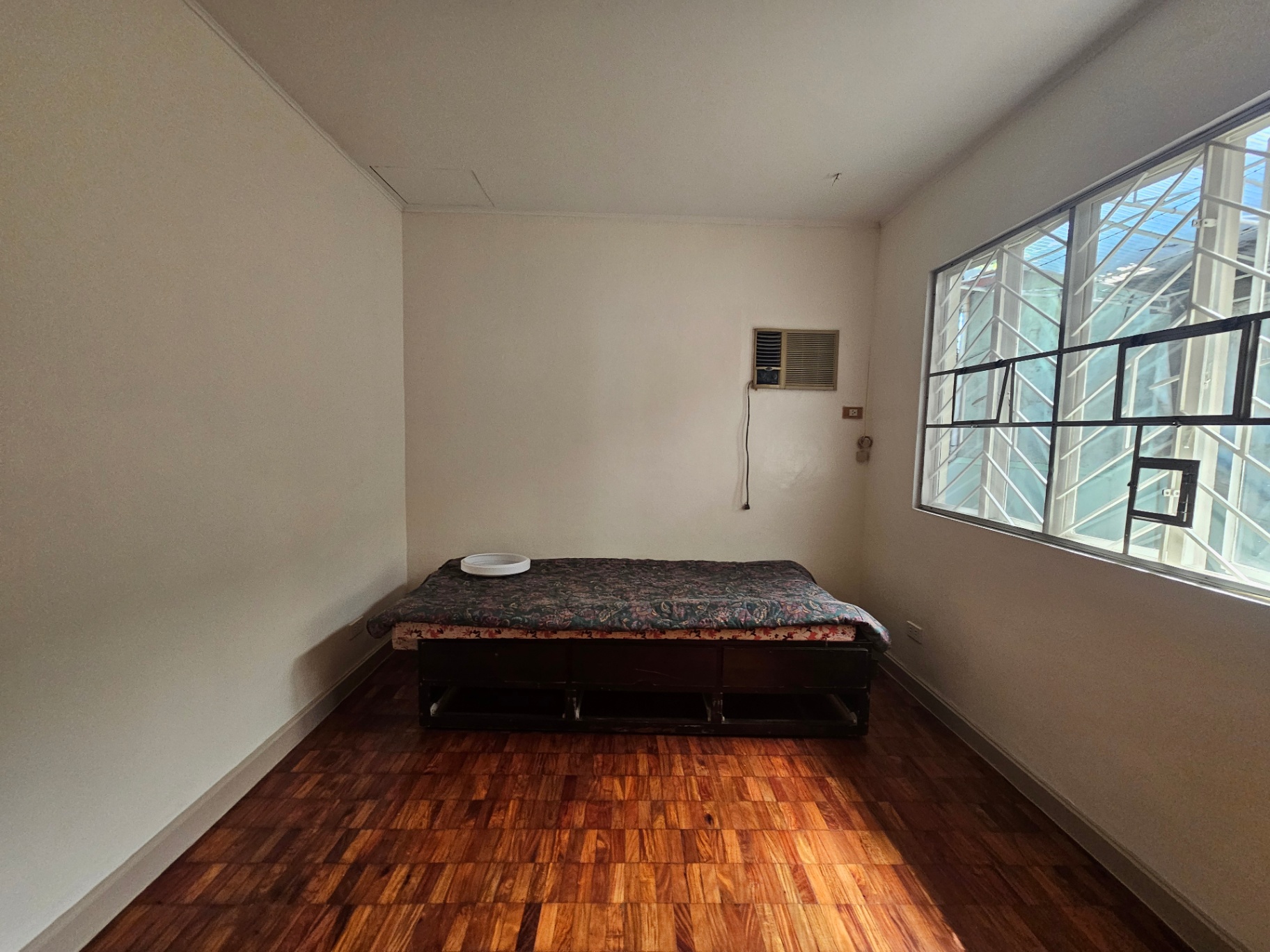 Furnished bedroom with parquet floors and large steel-frame windows
