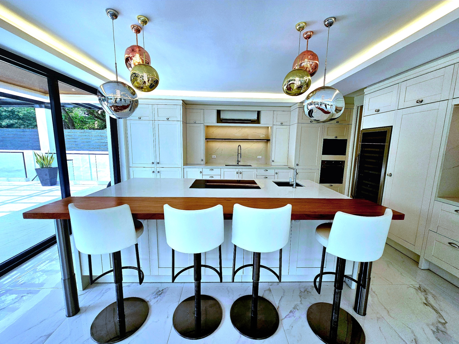 Elegant kitchen island with white marble counter, copper and chrome pendant lights