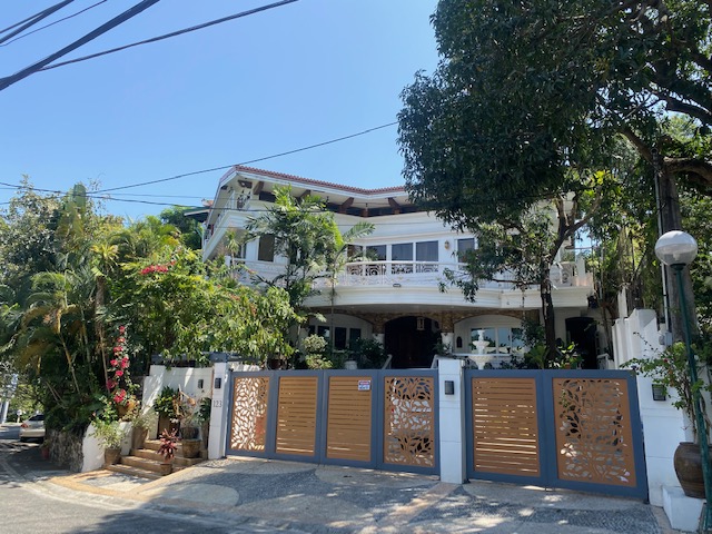 Street view of the elevated estate behind its landscaped wall and gate
