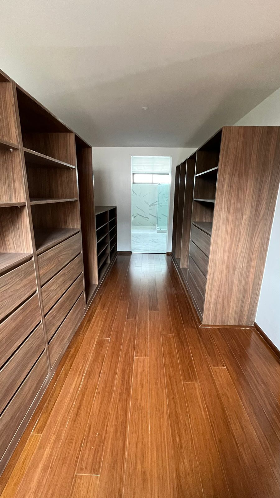 Walk-in closet with custom hardwood cabinetry, open shelving, and built-in dressers