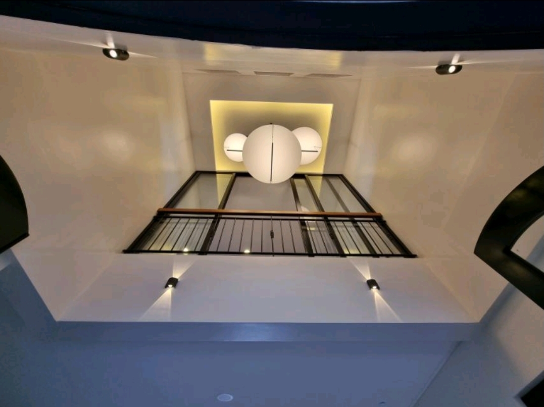 Double-height interior volume with upper gallery and pendant lighting