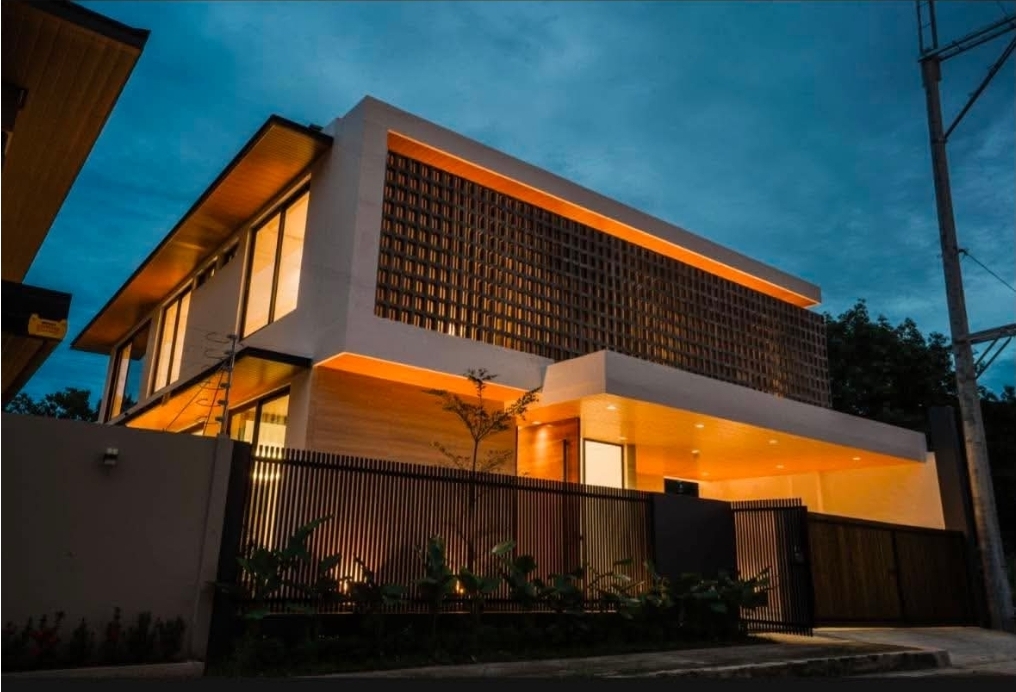 Dusk view of the facade with warm cove lighting under the breeze-block screen