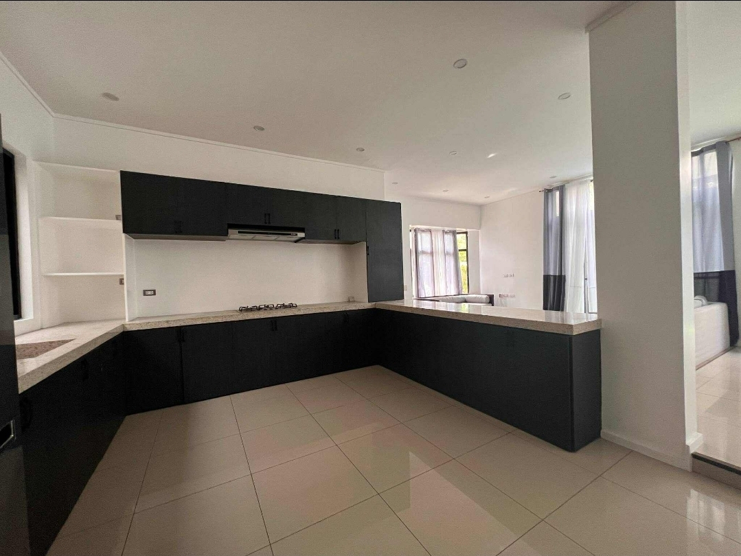 L-shaped kitchen with black cabinetry, gas range, and rangehood