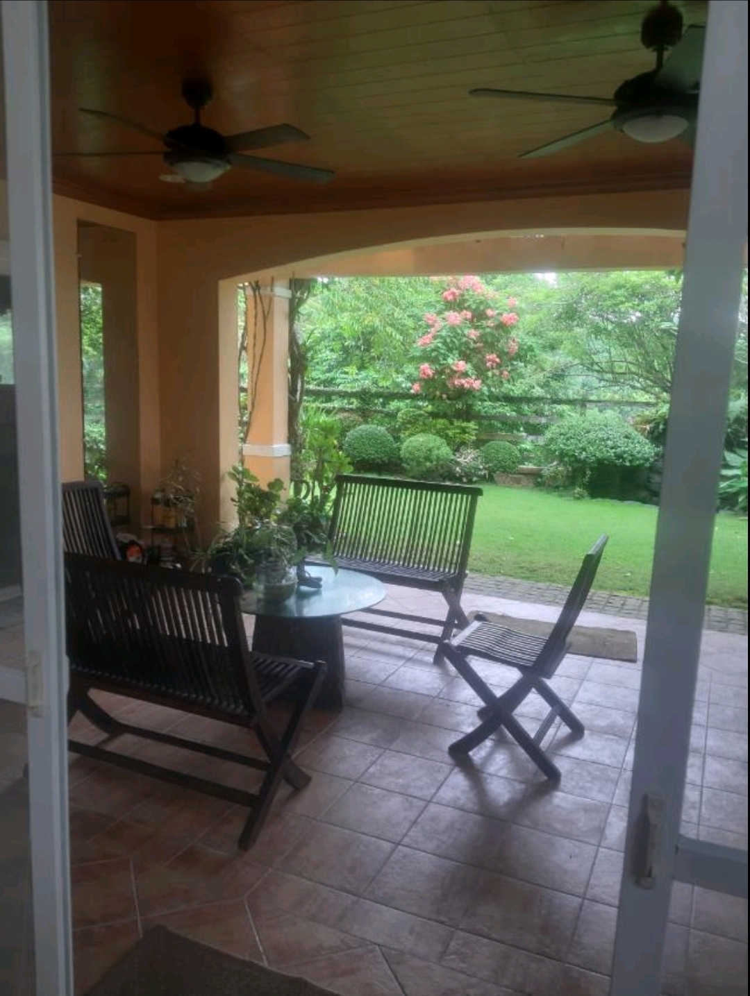 Covered patio with ceiling fans opening to the fully landscaped rear garden