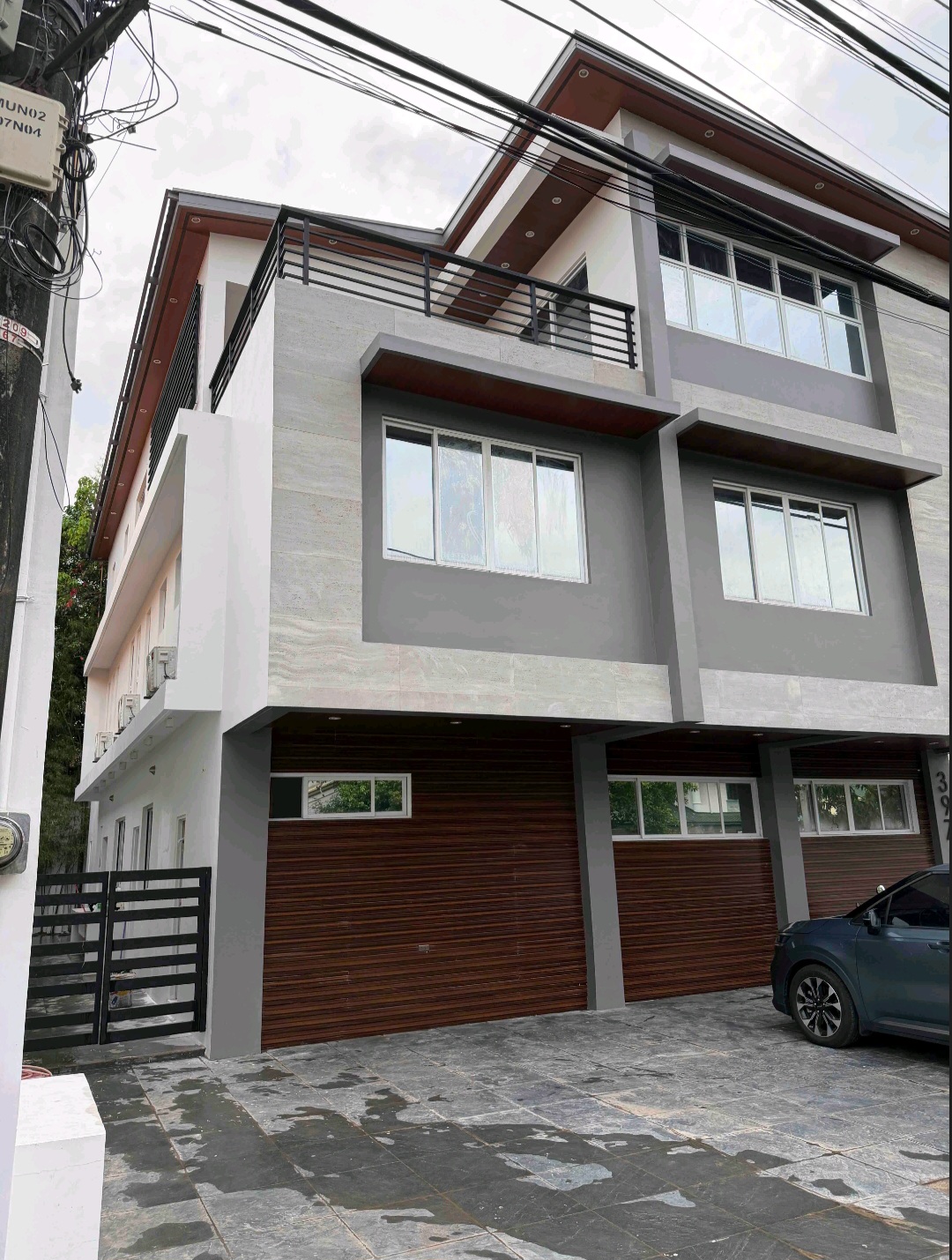 Street view of the three-storey residence with balcony and multi-car garage