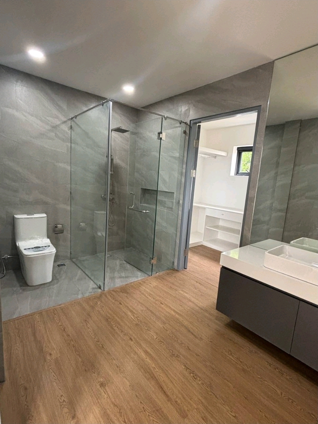 Toilet and bath with walk-in glass shower and walk-in closet beyond