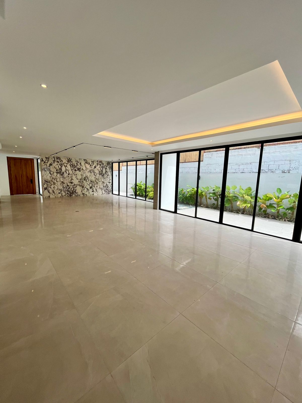 Expansive living area with polished porcelain floors opening to the garden through sliding glass walls