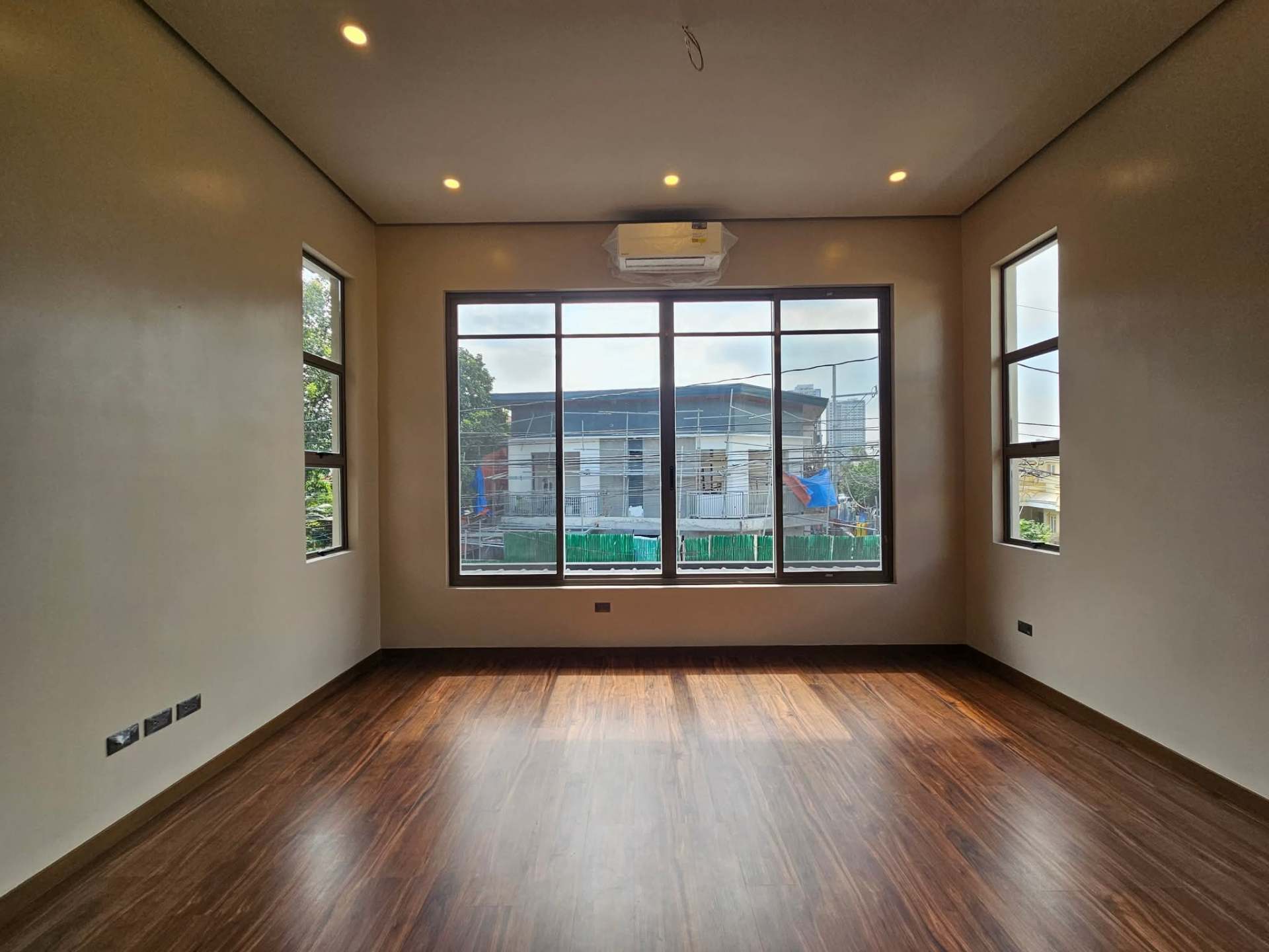 Spacious bedroom with wide windows and warm wood flooring
