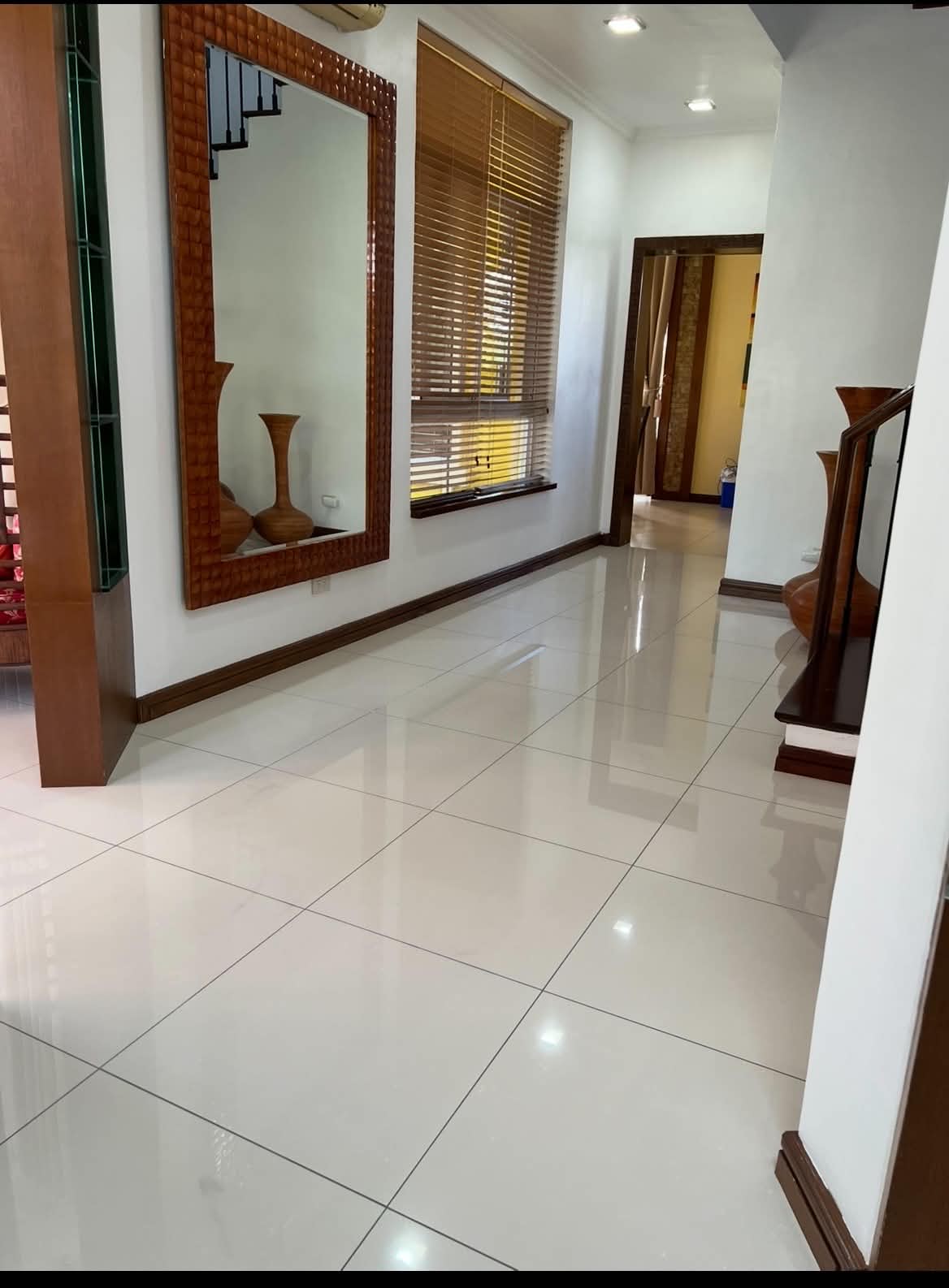 Bright hallway with polished tile floors and carved wood-framed mirror