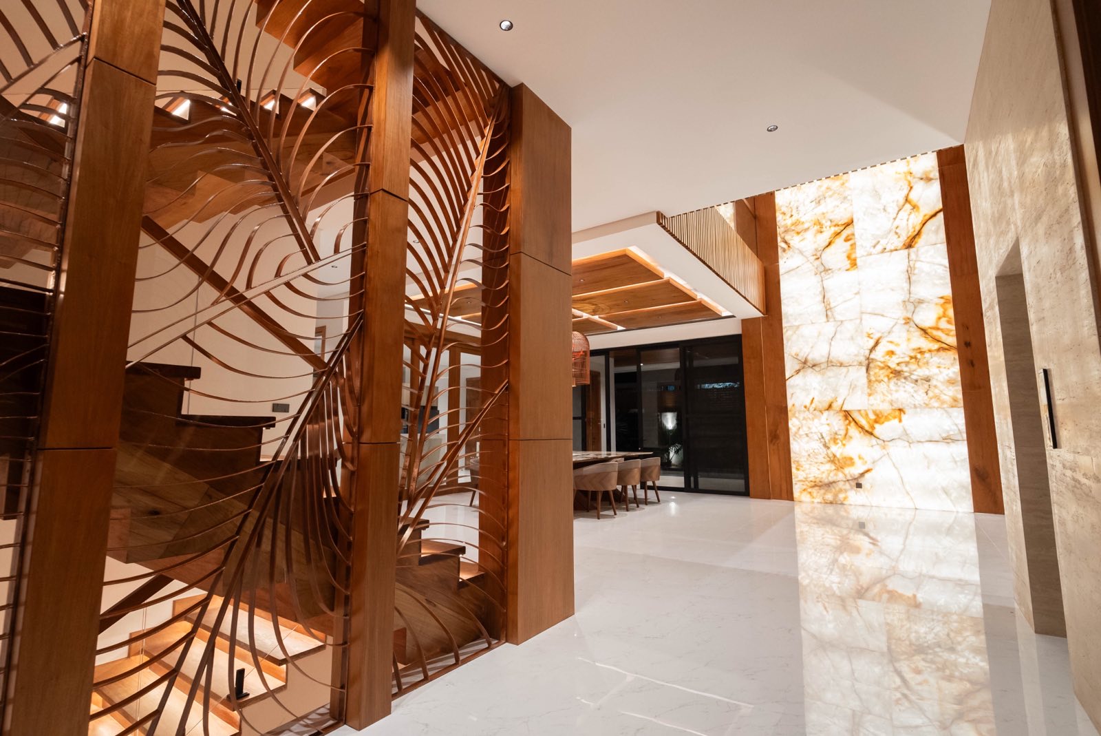 Foyer with floating Indonesian narra staircase and backlit Patagonia stone wall