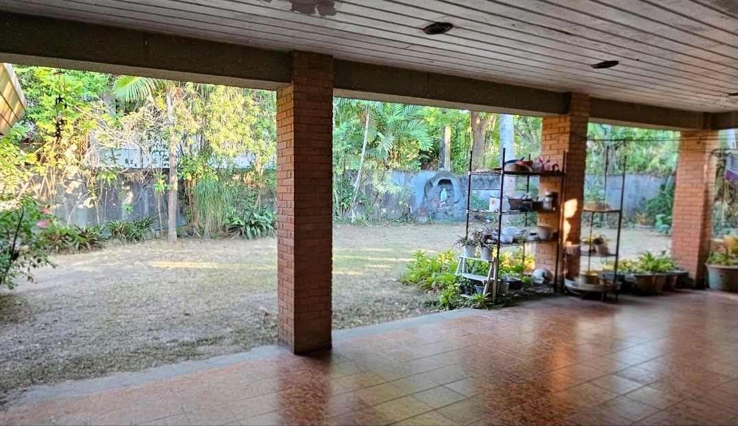 Expansive covered lanai with tiled flooring overlooking a leafy landscaped garden