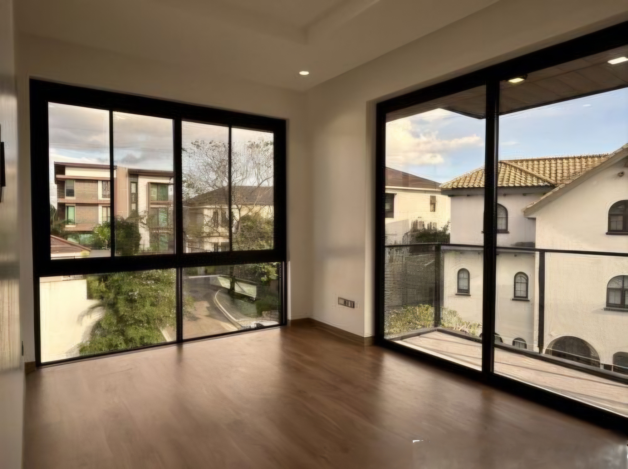 Bright bedroom with floor-to-ceiling corner windows and hardwood floors