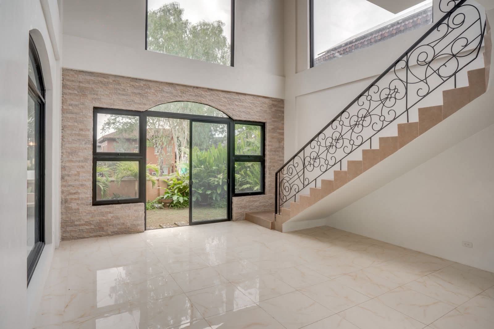 Living area with sweeping wrought-iron staircase and garden access