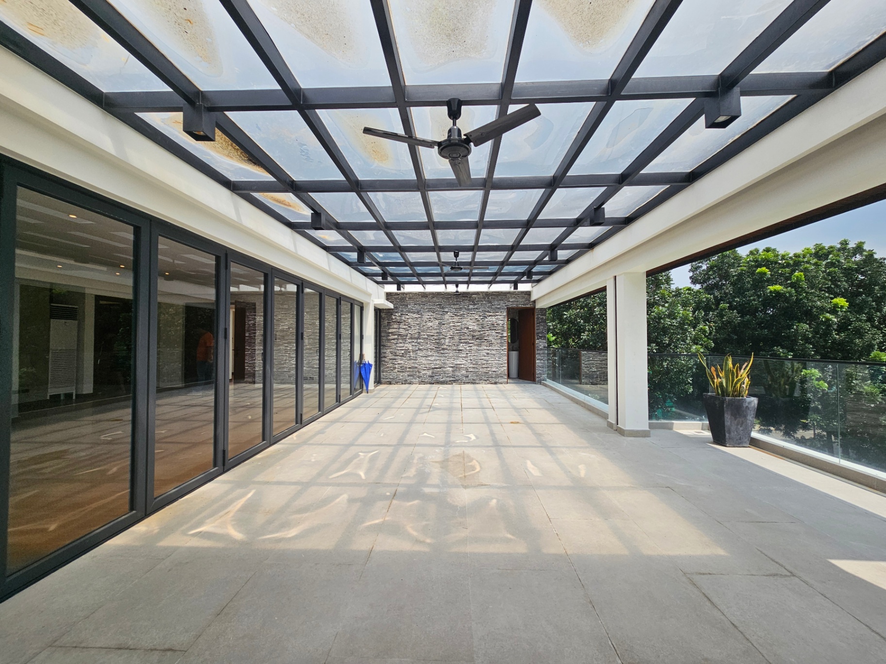 Covered terrace with steel-and-glass canopy and garden views