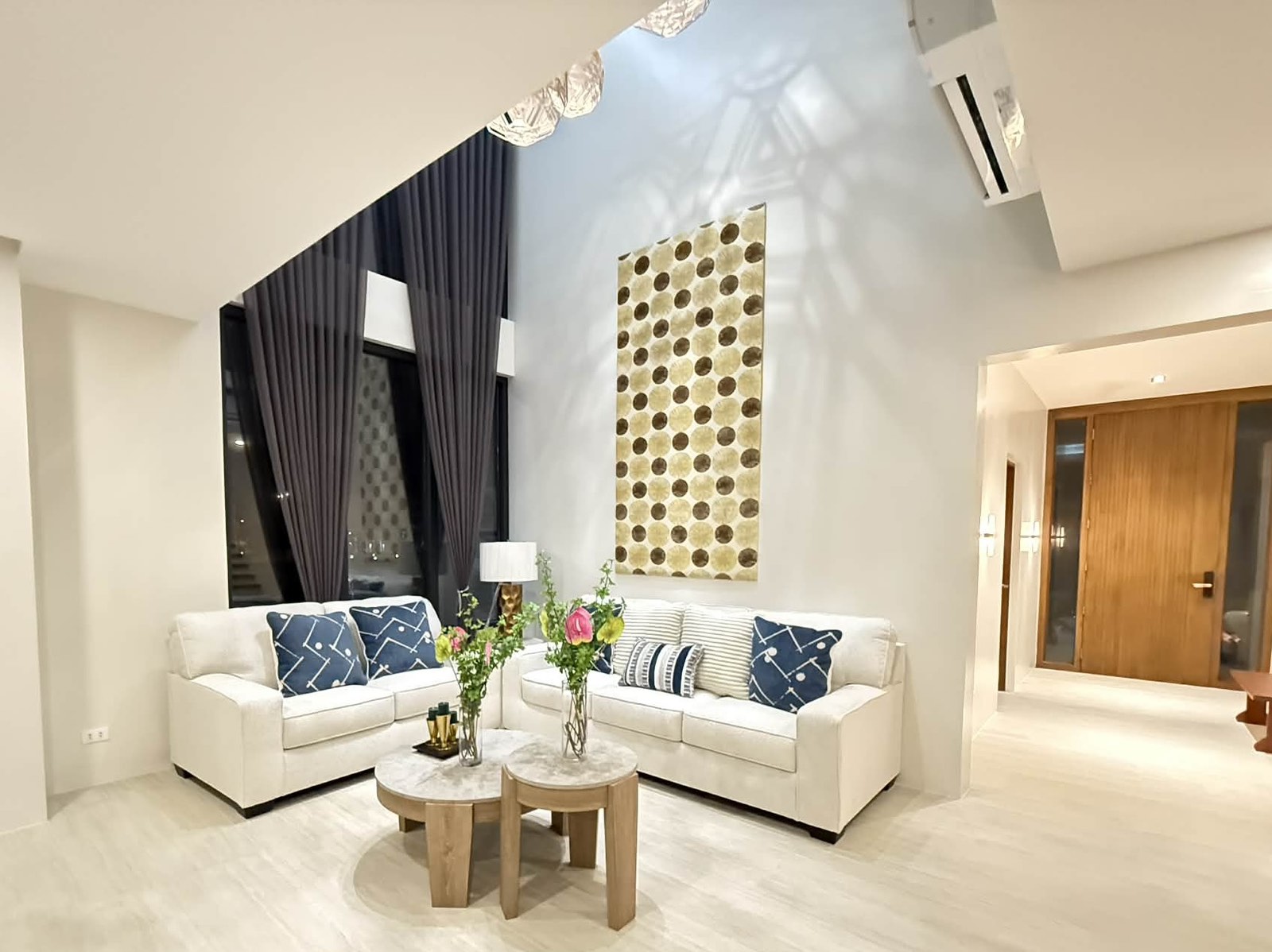 Cathedral-ceiling living room with twin sofas and floor-to-ceiling drapes