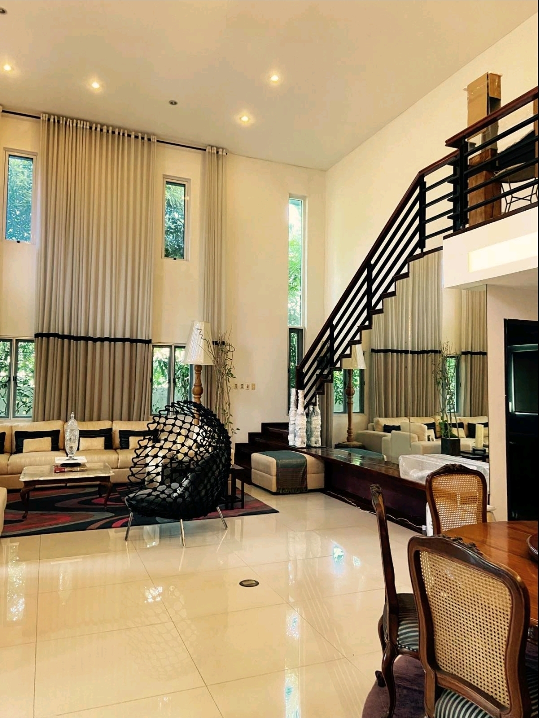 Double-height living area with dramatic wood staircase leading to a loft