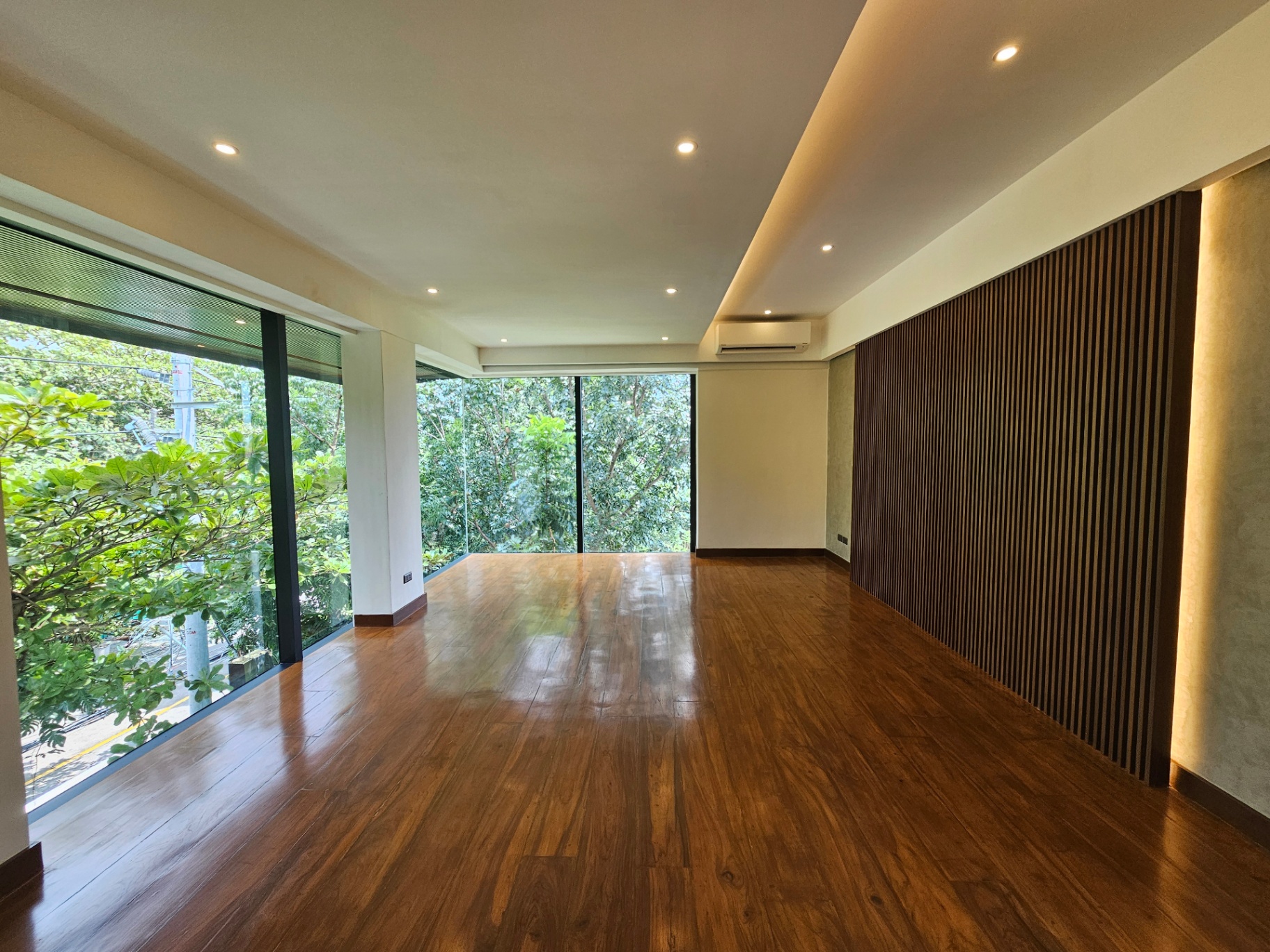 Contemporary room with floor-to-ceiling glass overlooking lush greenery